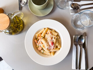 Overhead view of pasta with vegetables and grated cheese on white plate. Culinary scene symbolizing gourmet cuisine, nutrition and lifestyle dining.