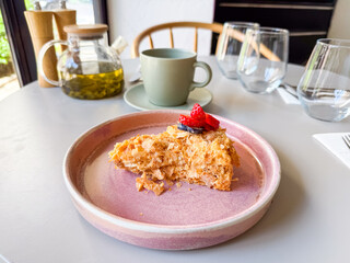 Slice of layered cake with berries served with tea in cafe. Dessert and beverage symbolizing sweet indulgence, lifestyle dining and culinary culture.