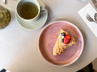 Overhead view of cake slice with fresh berries and tea cup on table. Sweet dessert symbolizing indulgence, lifestyle dining and gourmet culture.