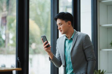 Asian businessman using smartphone near window in office