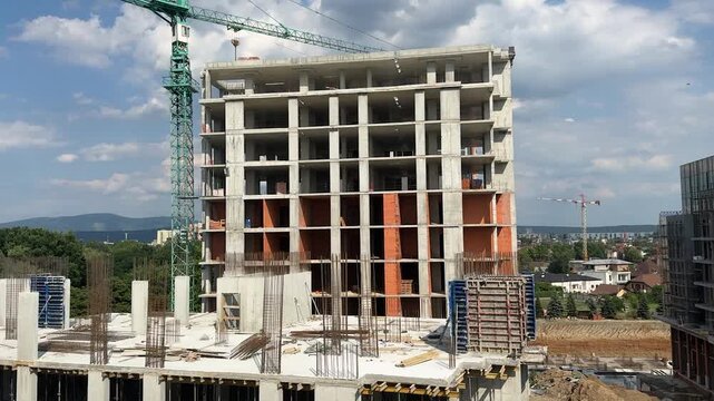 A large unfinished building under construction with a crane towering beside it