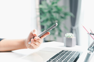 Close-up scene, a female seated at a table holds a smartphone, spending time on modern e-date...