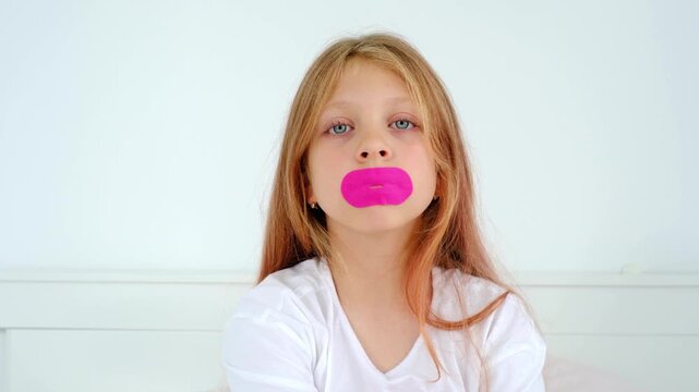 Sleeping with your mouth taped shut. A child's dream. The girl puts a Band-Aid on her mouth. The habit of breathing through your nose. The adenoid. Somnology. ENT diseases. Medical Tech. sstkHealth