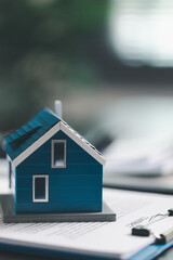 Real estate agent and customer are discussing contract to buy house, with house model in background...