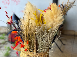 Textured bouquet of pampas grass and assorted dried stems in a woven basket, shot in shallow depth...