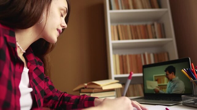 distance learning online education. school girl student studying at home on a laptop watching an online seminar near a bookcase desk online. distance education concept. teen girl on an online exam - Powered by Adobe