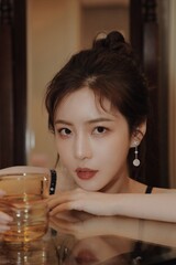 Portrait of a young woman with dark hair holding a glass of beverage in a modern indoor setting.