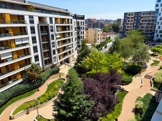 Modern apartment complex with landscaped courtyard, greenery and walking paths viewed from above....