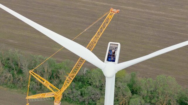 Drone view wind park construction with crane and turbine workers close up.