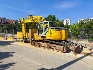 Yellow excavator at construction site. Urban development, infrastructure, and heavy machinery in city environment during daytime work.