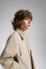 Stylish boy in a beige shirt with a modern look and thoughtful expression.
