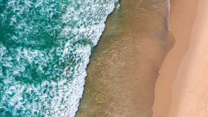 Top view beach with waves crashing on sandy shore