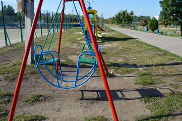 Fototapeta premium colorful metal swing set in a public park, playground equipment for children, outdoor recreation and leisure area