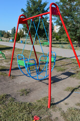 Fototapeta premium colorful metal swing set in a public park, playground equipment for children, outdoor recreation and leisure area