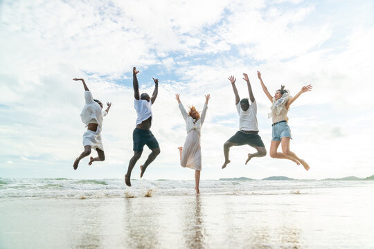 Group of Happy diverse people friends travel the sea on summer beach holiday vacation. Man and woman friendship enjoy and fun active lifestyle celebration beach party and playing together in the sea.