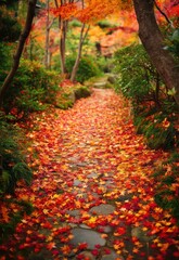 A serene pathway winds through a Japanese garden, blanketed in a vibrant carpet of fallen maple leaves. The path, constructed of moss-covered stones, leads the eye deeper into the scene.
