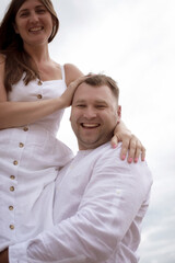 Man holding woman in arms, they laugh, sky background