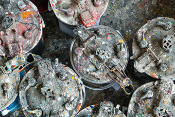 a cluster of paint-splattered cans on a messy studio floor