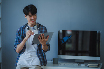 Young man working from home, using a digital tablet and stylus pen, focused on tasks in a comfortable home office environment