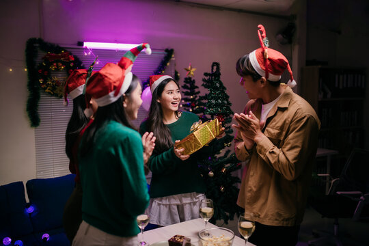 Friends exchanging gifts and celebrating Christmas together at home - Powered by Adobe
