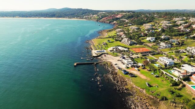 Aerial view of Punta Ballena waterfront with houses, tennis courts, pier, and coastline