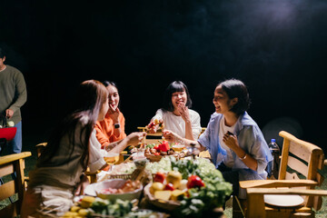 Friends enjoying barbecue party at night, eating and laughing together