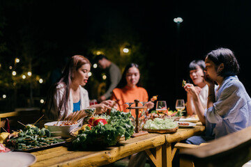 Friends enjoying barbecue dinner party at night