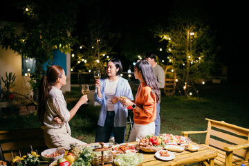 Friends enjoying garden party with food and drinks at night