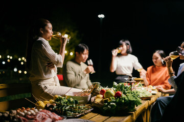 Friends drinking wine and eating together at night outdoor party