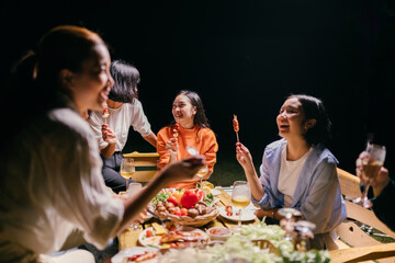 Friends enjoying barbecue party at night with skewers and wine