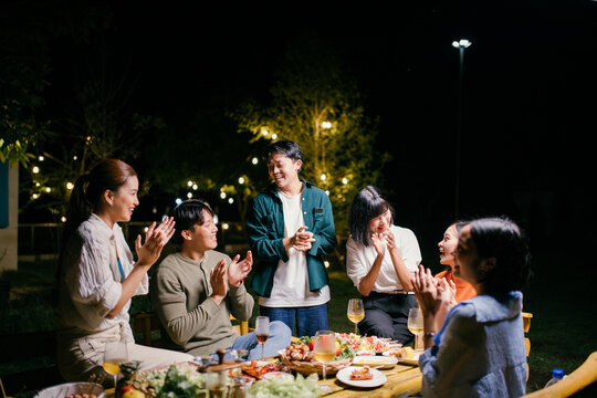 Friends clapping hands, enjoying garden party at night