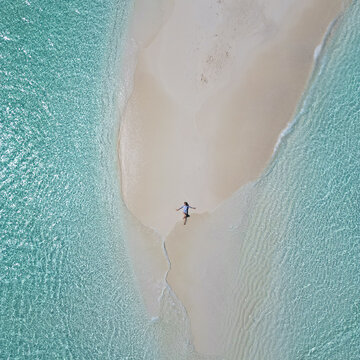 Woman enjoys the crystal-clear water of Maldives by laying on the sandbank in the middle of nowhere 
