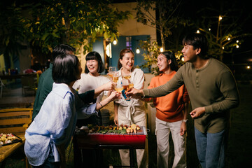 Asian friends toasting wine glasses at barbecue dinner party