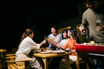 Friends toasting wine glasses during a barbecue dinner party
