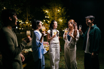 Friends enjoying drinks at a night garden party under string lights