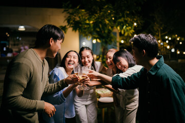 Friends toasting together during a night party in the garden