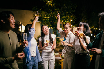 Group of friends raising glasses celebrating at outdoor party at night