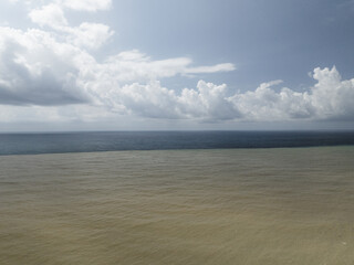 Aerial view of the stark contrast between the muddy river outflow and the dark sea under a cloudy sky, Kobuleti, Adjara, Georgia.