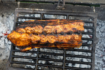 Appetizing close-up of pork ribs cooking on a grill; smoky glaze, seared crust and dripping juices...