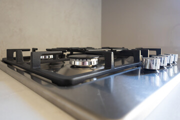 Stainless gas cooktop with four burners and cast-iron grates set into a modern kitchen countertop