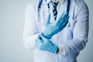 Doctor wearing sterile gloves with stethoscope on light background
