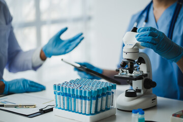 Medical Scientists Discussing Test Results Using Microscope in Laboratory