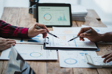 Business people analyzing financial charts and graphs using pens and digital tablet at wooden table