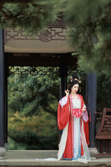 Elegant woman in traditional hanfu costume standing gracefully outdoors Chinese word means...
