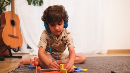 Young child playing with building blocks while listening to music on headphones