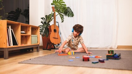 Young child playing with building blocks and listening to music on headphones