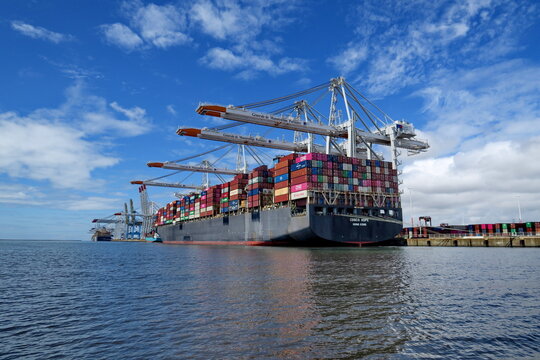Cargo porte-container sur un quai de d&eacute;chargement avec portique g&eacute;ant. Port du Havre. Normandie. France. 17 Juillet 2025.