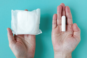 Feminine sanitary pad and tampon for intimate hygiene in Caucasian woman's packaging. Turquoise background.