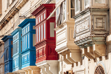 Traditional Maltese wooden balconies painted in vibrant colors on limestone facades, typical...