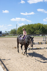 Little girl riding a horse alone in outdoor arena
